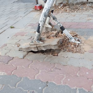 עמוד מתכת שבור על מדרכה עם אבנים שבורות