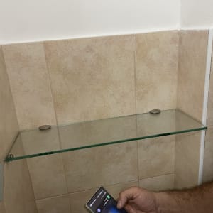 מדף זכוכית מותקן על קיר בחדר אמבטיה