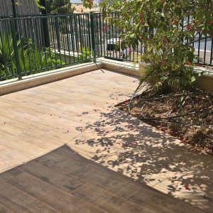 ריצוף עץ חדש במרפסת עם צמחייה מסביב