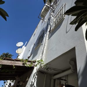 חזית בניין מגורים מתוחזקת וצבועה עם מזגנים וצנרת בגובה