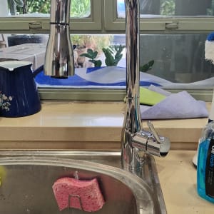 ברז נירוסטה מעל כיור מטבח עם ספוג ורוד