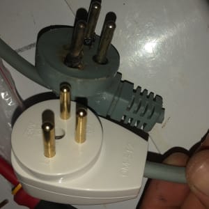 תקע חשמלי עם שלושה פינים ביד חשמלאי