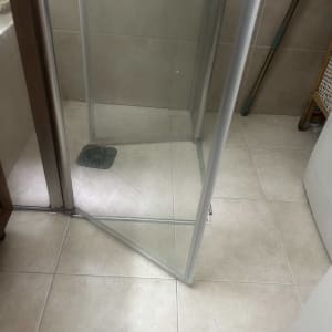 מקלחון עם דלת זכוכית פתוחה ורצפת אריחים