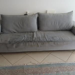 ספה אפורה עם כתמים על רצפת קרמיקה