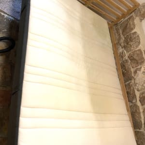 מזרן לבן עם כתמים על מסגרת עץ