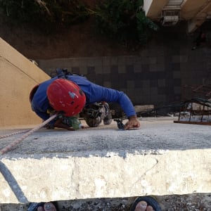 עובד בגובה עם קסדה אדומה מטפס על בניין