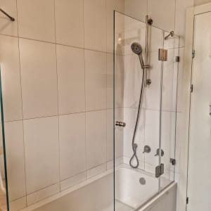 מקלחת עם דלת זכוכית וראש מקלחת מתכתי