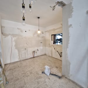 חדר ריק בשיפוץ עם קירות חשופים ותאורה תלויה