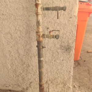 צינור חלוד עם ברזים על קיר בטון