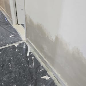 קיר צבוע חלקית עם יריעת מגן על הרצפה