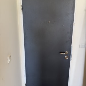 דלת מתכת עם ידית כסופה וקיר לבן