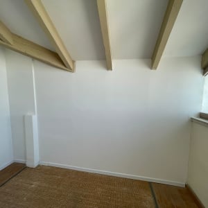 קיר גבס לבן עם קורות עץ בתקרה