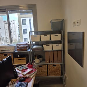 מדף עם קופסאות וציוד משרדי בחדר עבודה.