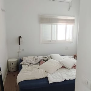 חדר שינה עם מיטה מבולגנת ומאוורר תקרה