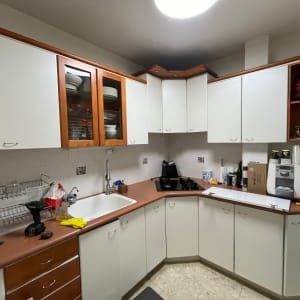 מטבח עם ארונות לבנים, כיור וברז, כלים על השיש