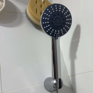 ראש מקלחת וספוג במקלחת על קיר אריחים לבן
