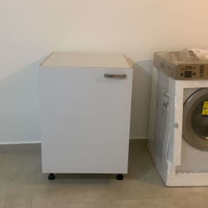 ארון מטבח לבן ליד מכונת כביסה באריזה