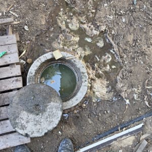 שוחת ביוב מוצפת ומלאה במי שפכים ומגבונים לפני פתיחת סתימה