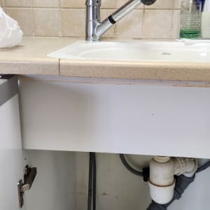 כיור מטבח עם ברז, צנרת מתחת לארון פתוח