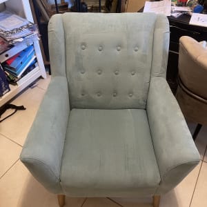 כורסה ירוקה עם רגלי עץ על רצפת אריחים