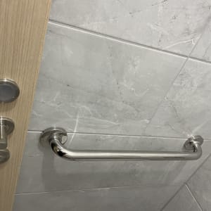 ידית אחיזה מתכתית על קיר אריחים בחדר אמבטיה