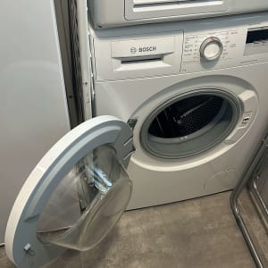 מכונת כביסה פתוחה על רצפת אריחים אפורה