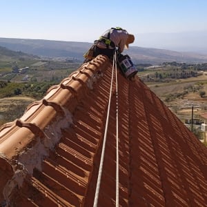 אדם עובד על גג רעפים עם חבל בטיחות