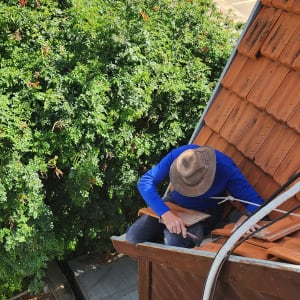 אדם עובד על גג רעפים עם כובע רחב שוליים