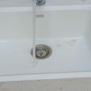 ברז מים זורם בכיור לבן עם ניקוז מתכת