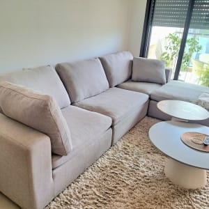 ספה אפורה עם שולחנות עגולים בסלון מואר