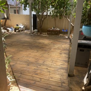 דק עץ בגינה עם עצים ונדנדה