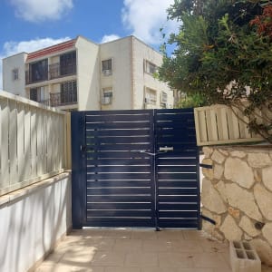 שער אלומיניום בחצר עם בניין ברקע