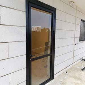 דלת אלומיניום שחורה מותקנת בקיר חיצוני