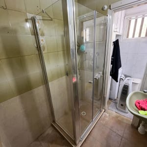 מקלחון זכוכית עם דלתות מתכת בחדר אמבטיה