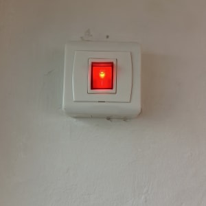 מתג חשמלי עם אור אדום על קיר לבן
