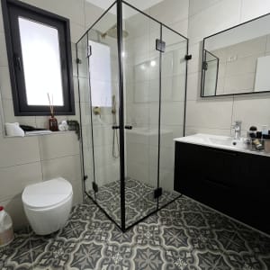 מקלחון זכוכית עם מסגרת שחורה בחדר אמבטיה מודרני