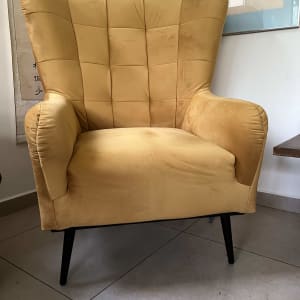 כורסה מרופדת בצבע צהוב עם רגליים שחורות