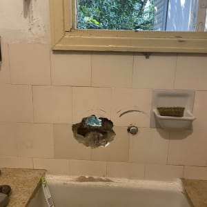 חור בקיר מעל כיור עם כלים לעבודת אינסטלציה