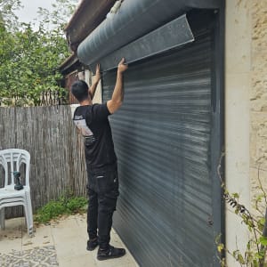 אדם מתקין תריס גלילה חיצוני על קיר אבן