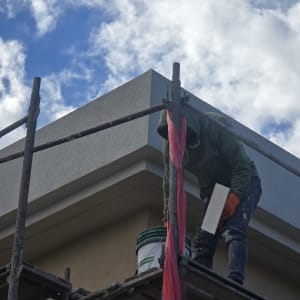 אדם עובד על פיגום עם דלי צבע