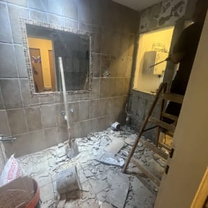 חדר בשיפוץ עם אריחים שבורים, סולם וכלי עבודה