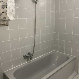 אמבטיה עם אריחים אפורים ומקלחת יד