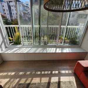 חלון גדול עם אדן עץ וצמחייה בחוץ