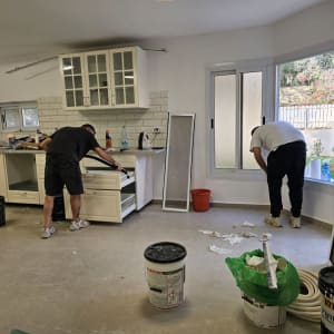 שני אנשים מנקים מטבח עם כלים וחומרי ניקוי