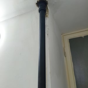 צינור שחור מותקן בתקרה לבנה