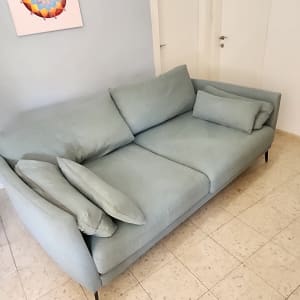 ספה ירוקה עם כריות על רצפת אריחים