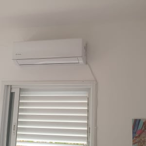 מזגן לבן מותקן על קיר מעל חלון