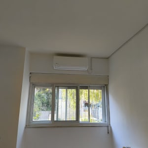 מזגן מותקן על קיר מעל חלון בחדר