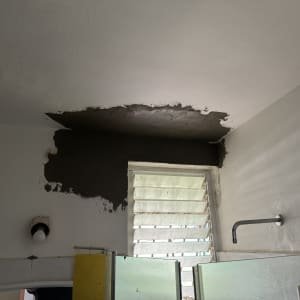 עבודת תיקון וטיוח בתקרה ובקיר בחדר רחצה במהלך שיפוץ