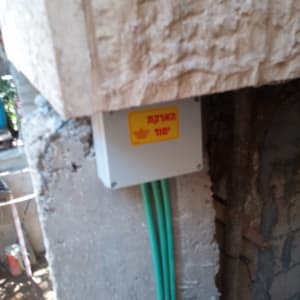 קופסת חשמל עם כבלים ירוקים וקיר בטון